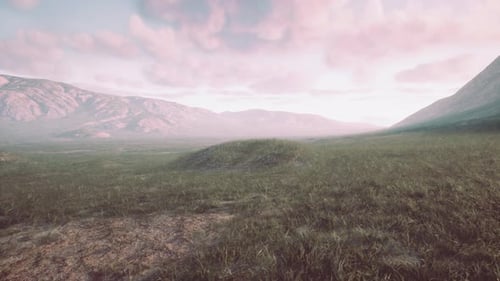A Picturesque Field with Majestic Mountains As the Backdrop
