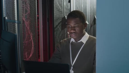 Young Black Male IT Engineer Working on Laptop in Data Center