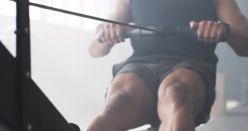 Using rowing machine, man exercising in gym, focusing on fitness and strength