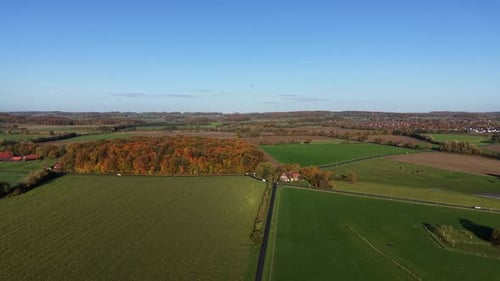 Rural Farmland fields with driving cars on intersection road. Sunny day with blue sky in fall