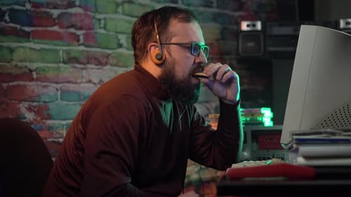 Man Working on a Computer and Eating a Cookie