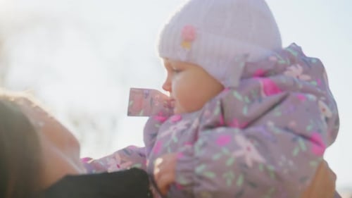Mother Holding her Baby Outside in Winter