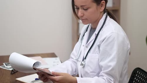 Female Doctor in Modern Clinic Dedicates Herself to Examination of Patient Test Results