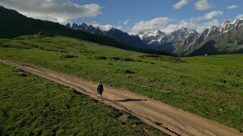 Aerial View of Man Hiking Alone on Alpine Meadows in High Mountains Solitary Male Trekker Walking