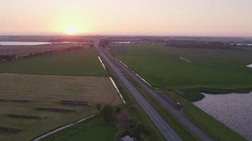 Aerial view of serene sunset over lake and road, Netherlands.