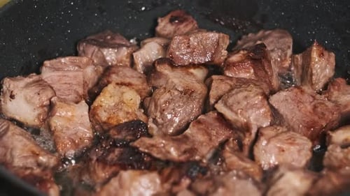 Juicy Pieces of Pork Meat are Cooked in a Frying Pan in a Home Kitchen