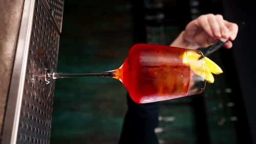 Vertikale Video-Nahaufnahme eines Weinglases auf schwarzem Hintergrund mit grob zerkleinertem Eis in einem Glas