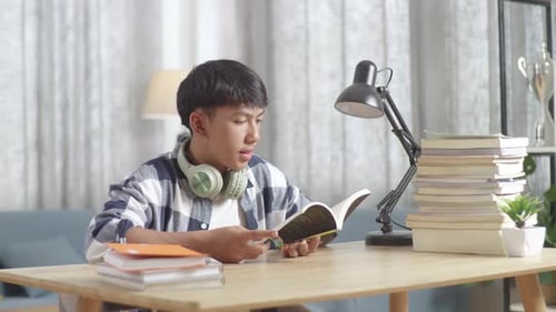 Asiatisches Teenager-Lesebuch im Wohnzimmer, Asiatische Teenager lernen zu Hause