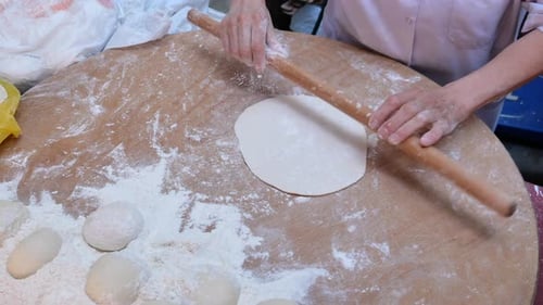 Baker Rolling Dough with Wooden Rolling Pin