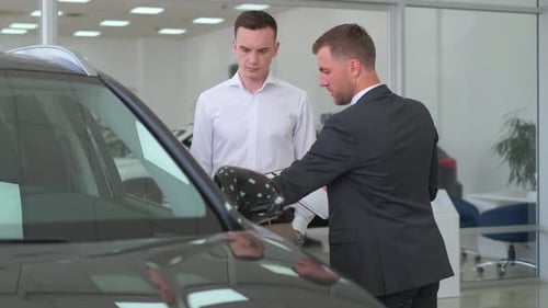 Salesman and Customer Examine New Car at Dealership