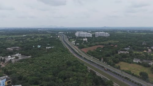 Wide-angle drone footage of a road in Amaravathi surrounded by farmlands and greenery.