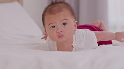 Cute Infant Lays on Bed, Looking Around
