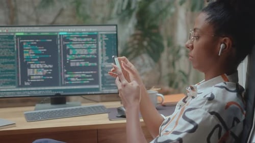 Female Programmer Texting on Smartphone at Workplace