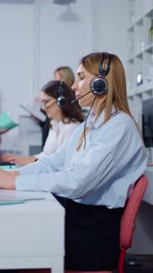 Professional Customer Support Agents Working at Computers with Headsets in a Modern Office Focusing