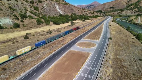 Aerial View of Freight Train and Highway in Mountains
