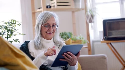 Senior Woman Relaxing on Sofa Using Tablet