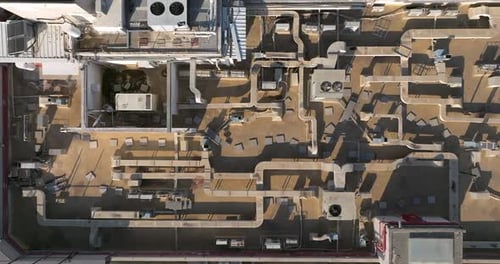 Industrial building rooftops with vents and pipes lined across, Top down view