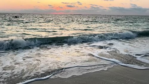 Slow Motion of Ocean Waves Rolling Onto Shore During Vibrant Sunset