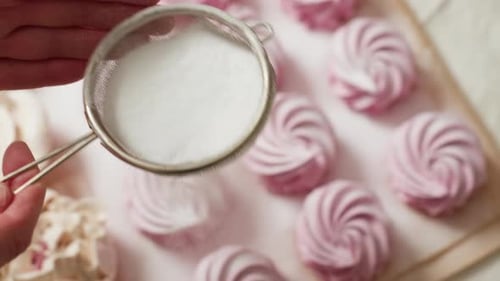 Baker Sprinkling Sugar Over Cupcakes in Neat Rows with Sifter