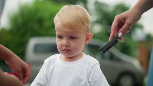 Little Boy Looks Lost in Thought While Someone Combs His Hair