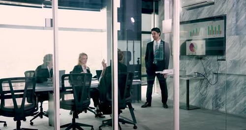 Diverse group of business professionals in formal suits seated around table in modern office