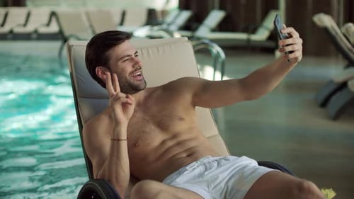 Fit Man Relaxing by Pool Taking Cellphone Selfie