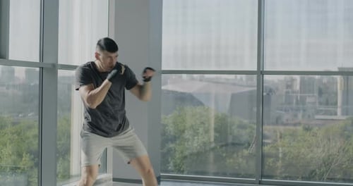 Professional Male Boxer Training Alone Throwing Punches Practicing Defense Moves in Gym