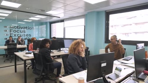 Colegas multiétnicos felizes discutindo e trabalhando em computadores em um espaço de trabalho criativo