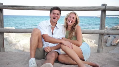 Joyful Couple Relaxing Together on a Sandy Beach During a Sunny Day Enjoying Their Carefree Vacation