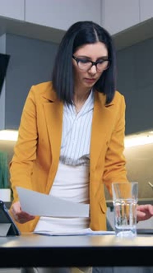 Focused Woman Reviews Documents and Works on Laptop