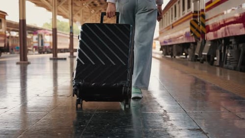 Traveler Pulling Rolling Suitcase Through Train Station