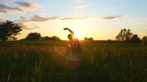 Silhouette of man doing early morning yoga against sunrise in rural fields