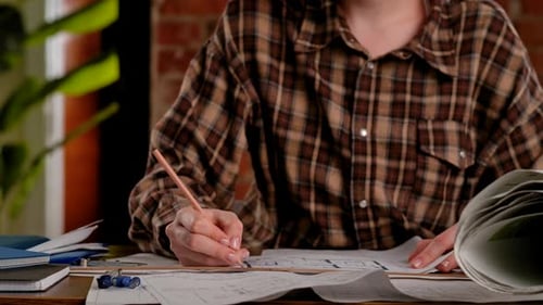 Person Reviewing Architectural Plans with Red Marker in Hand