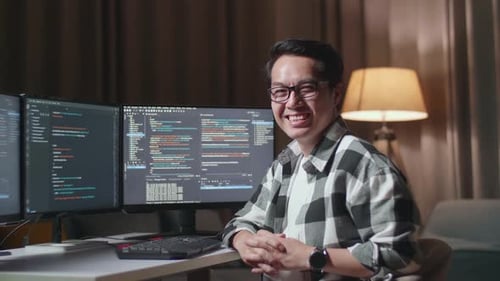 Asiatischer männlicher Programmierer lächelt in die Kamera, während er einen Softwareingenieur erstellt, eine App oder ein Programm entwickelt