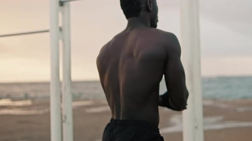 Muscular Man Doing Pull-Ups on Beach Workout Bar