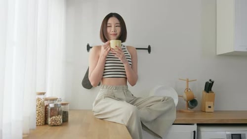 Woman Relaxes with Drink in Bright Kitchen