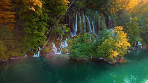 Waterfall flowing in autumn forest at national park during warm sunset light. Cascade in woods with