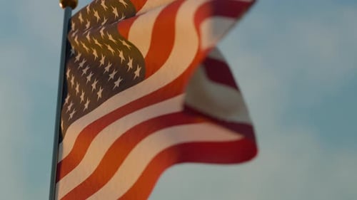 Realistic American Flag Waving against a Clear Blue Sky