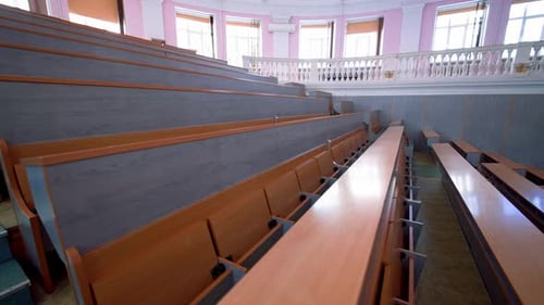 Rows of long desks in conference hall. Empty auditorium in the modern educational center.