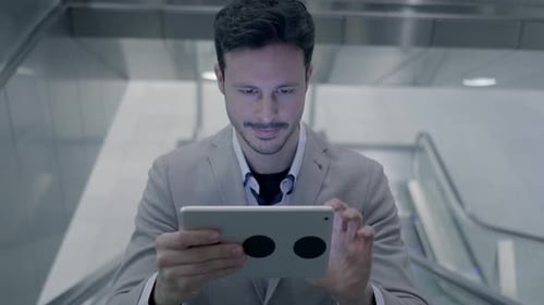 Man Using Tablet on Escalator in Urban Setting