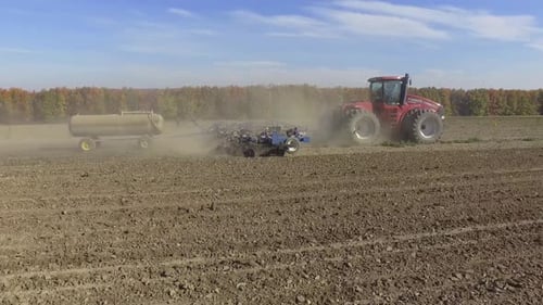 Big red tractor working on the field cultivating and applying nitrogen ASP