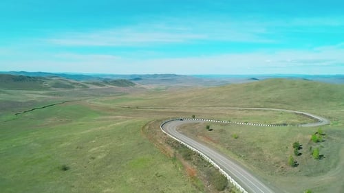 Aerial View of an Asphalt Road Through the Rural Countryside Area Wavy Road Between Little Hills