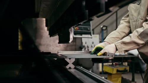 Stahlblecharbeiter in den Händen einer industriellen Biegemaschine, einer Fabrik für die Metallpresse, Industrieausrüstung