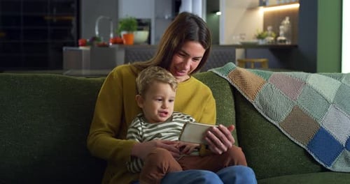 Smiling Mother and Child Watching Smartphone on Couch