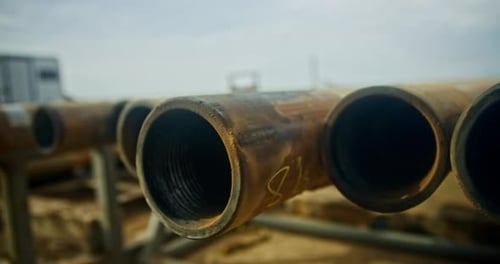 Metal rusty pipes lying in a row outdoors.