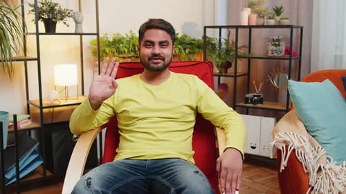 Smiling Man Waving Hello in Living Room