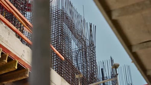 Construction site. Dense steel rebar grid rises above a city construction site, framed by formwork