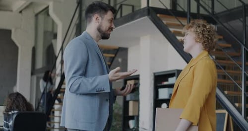 Businessman Talking to Female Colleague Laughing Shaking Hands Standing in Modern Office