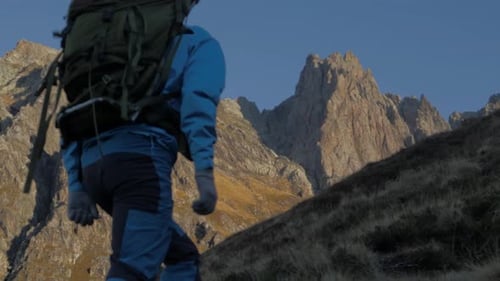 Slow motion tracking shot of man with backpack hiking in mountains of Norway
