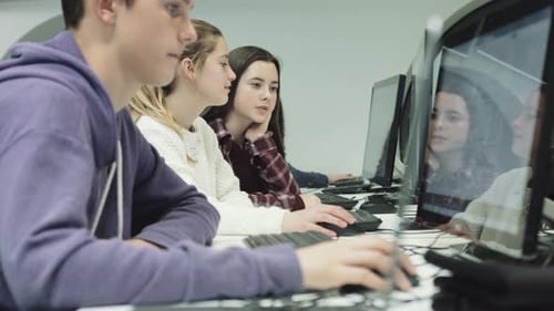 Teenage girls and boy working on computer in technology class